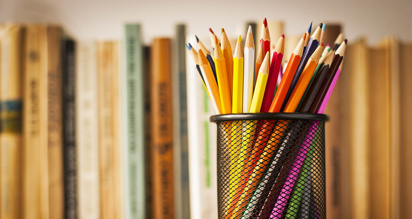 Colourful pencil crayons fill a metal cup.