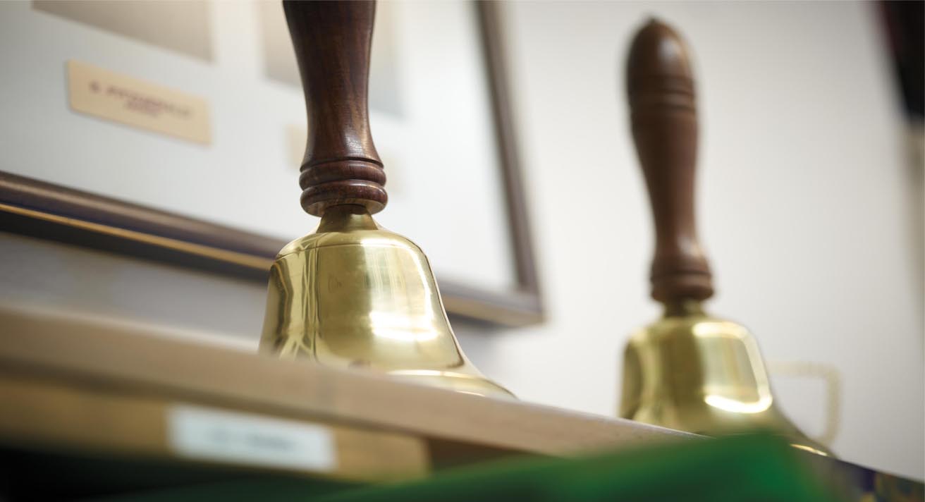 Two bells sit on a shelf.