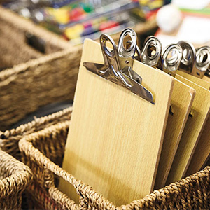 A wicker basket holds several wooden clipboards.